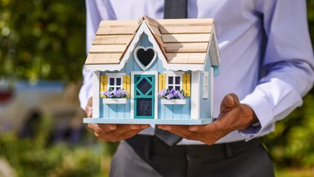 casa de madera en la mano de un agente inmobiliario